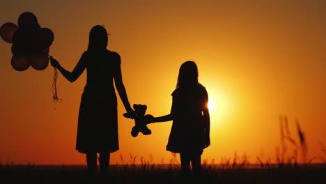 Middle-Aged-Woman-With-Her-Daughter-Admiring-The-Sunset-Holding-A-Teddy-Bear-Together