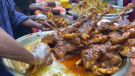 vendor pouring masala oil in spicy gravy chicken leg curry at a street market in india