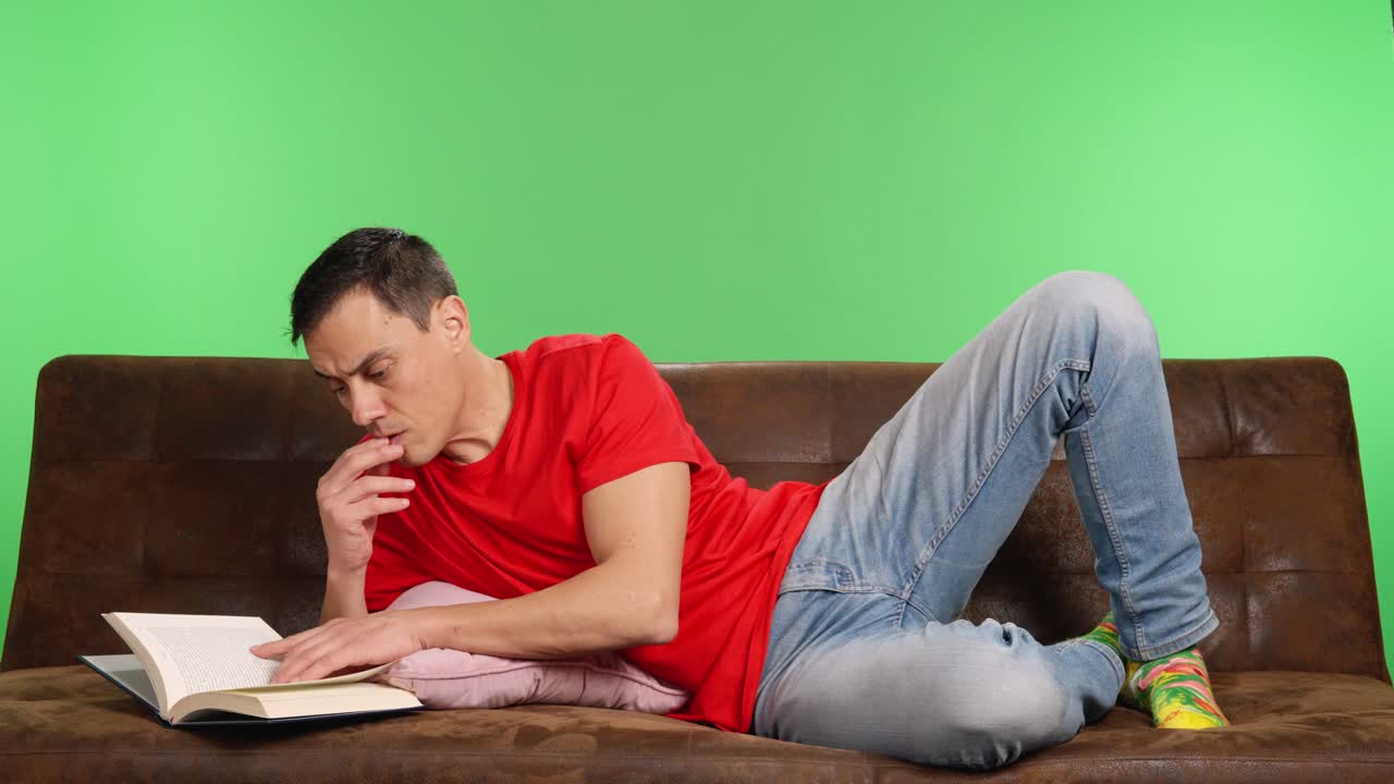 Man reading a book on a sofa with green screen background