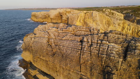 Vista-Aérea-De-Las-Olas-Del-Mar-Rompiendo-En-La-Costa-Rocosa-Al-Atardecer-1