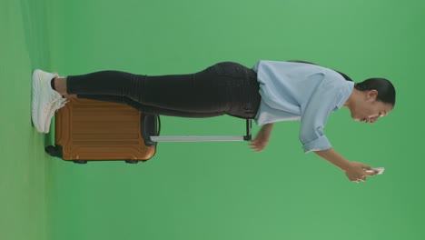 woman with suitcase looking at smartphone on green screen