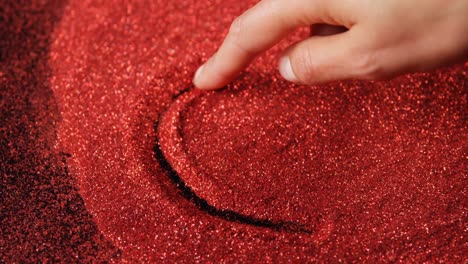 persona dibujando forma de corazón en brillo rojo 4k
