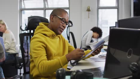 retrato de um empresário afro-americano sorridente sentado à mesa em um escritório moderno