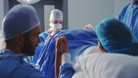 Caucasian-female-surgeon-examining-pregnant-woman-during-labor-in-operation-theater-at-hospital