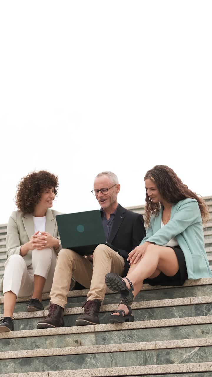 Business people having conversation sitting on steps. Vertical