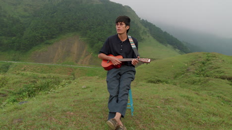 Joven-Macho-Genial-Tocando-El-Ukelele-Hawaiano-En-La-Cima-De-Una-Colina-Tropical