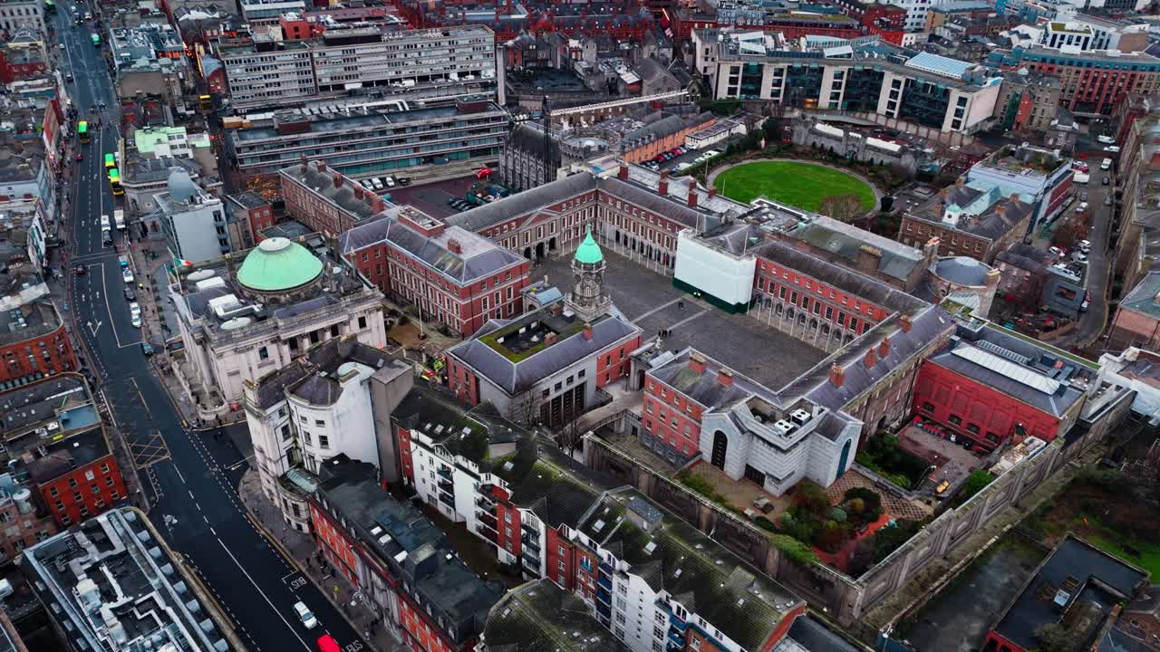 Droneopptak over Dublin Castle i sentrum av Dublin i Irland, med travle gater nedenfor med biler og busser og turister som spaserer rundt i det irske bybildet på en overskyet dag om vinteren