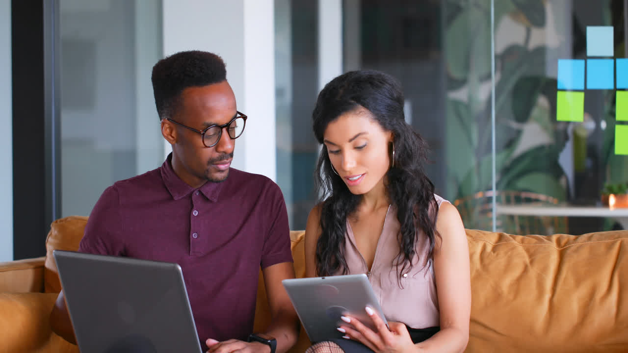 Executives discussing over digital tablet and laptop on sofa 4k
