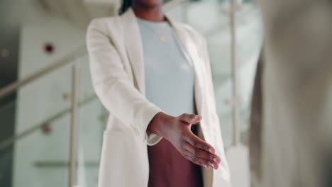 two businesswomen shake hands in an office setting