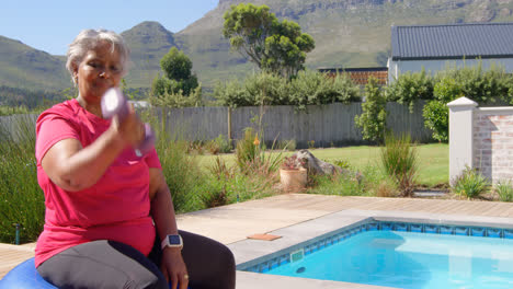 Side-vie-of-old-asian-senior-woman-exercising-with-dumbbells-in-the-backyard-of-home-4k