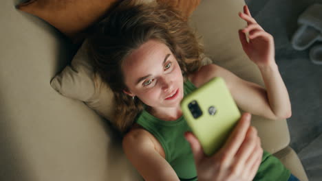 positive lady speaking cellphone video call closeup. relaxed woman laying sofa