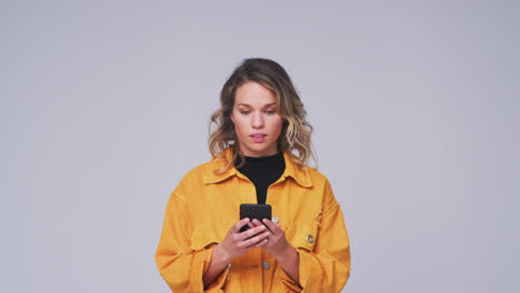 Studio-Shot-Of-Woman-Against-White-Background-Sending-Text-Message-On-Mobile-Phone-In-Slow-Motion