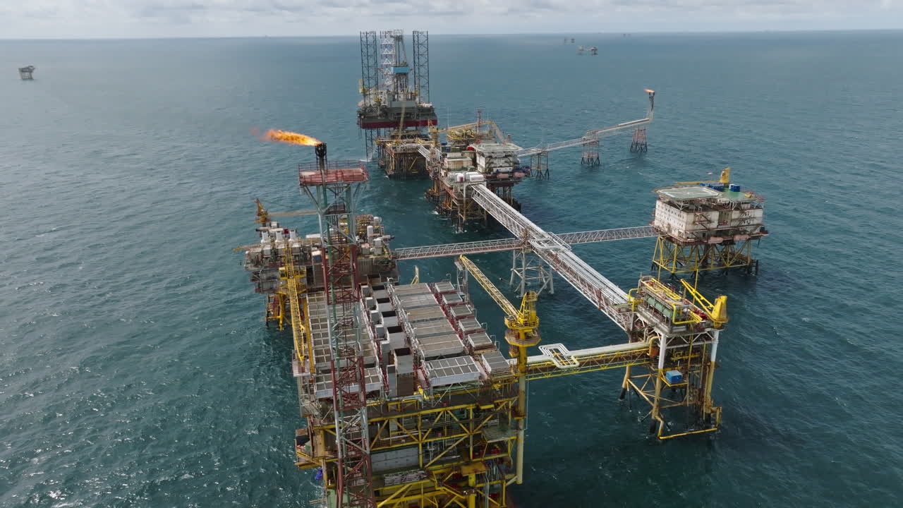 Çok sayıda gaz meşalesi bulunan devasa bir açık deniz işleme platformunun geniş açılı havadan görünümü, petrol endüstrisi.