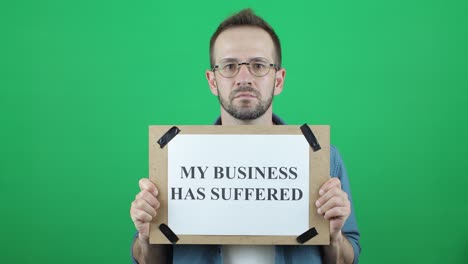 mi negocio ha sufrido. protesta pacífica. activista, hombre blanco, apariencia europea con la inscripción, una pancarta en mis manos "mi negocio ha sufrida" sobre un fondo verde