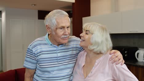 senior couple retired grandparents husband and wife happy faces embracing at home, hugging, laughing