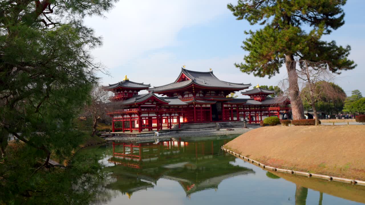 Veduta mattutina invernale dello storico tempio Byodo-in a Uji, Giappone, con il suo splendido riflesso nel lago. Si vedono i visitatori camminare e scattare foto intorno ai giardini del tempio.