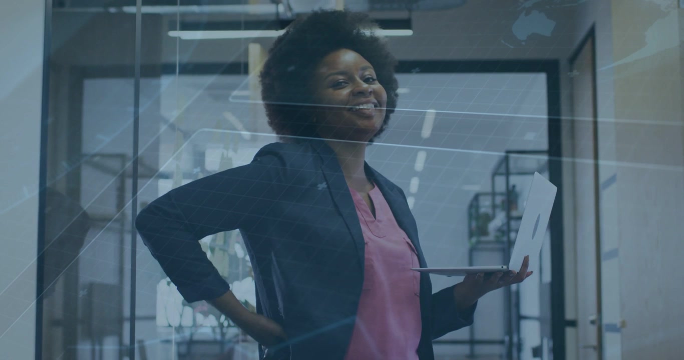 Vertical video: Typing woman in navy blazer pink blouse adjusting laptop at glass glare, presenting