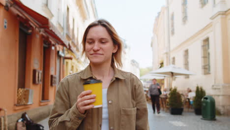 smiling woman walking on city street enjoying morning coffee hot coffee relaxing taking a break