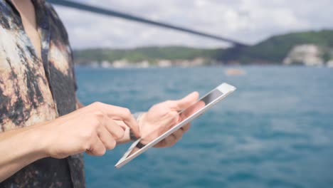 Working-on-tablet-by-the-sea,-tablet-close-up.