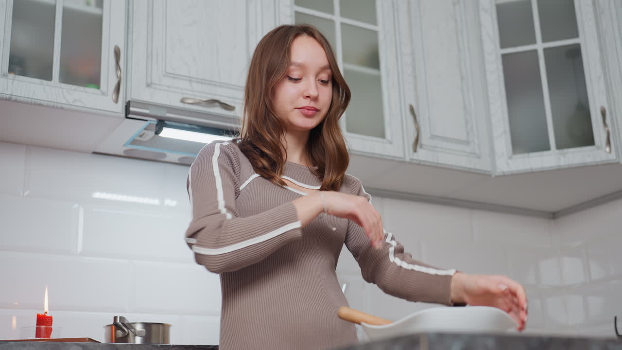 우아한 여성은 저녁 식사를 준비하는 동안 혼합물을 계속 기 전에 수갑을 조정합니다. 배경에는 색 캐비과 불타는 은 불이 있는 현대적인 부이 있습니다.