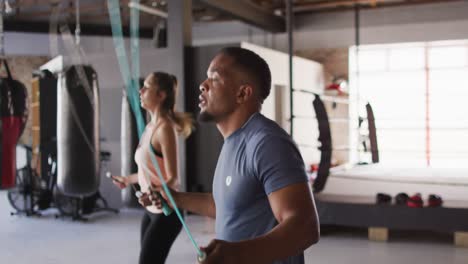 Video-Einer-Fitten,-Vielfältigen-Frau-Und-Eines-Mannes,-Die-Im-Fitnessstudio-Auf-Einem-Springseil-Springen