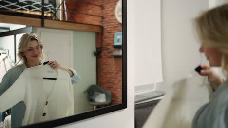 blond chooses clothes in the wardrobe at home. a woman tries on a white jacket