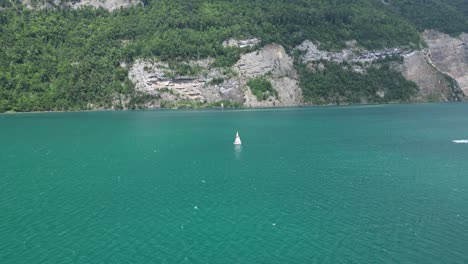 Einsame-Yacht-Segelt-Im-Türkisfarbenen,-Ruhigen-Wasser-Des-Schweizer-Sees,-Aus-Der-Luft