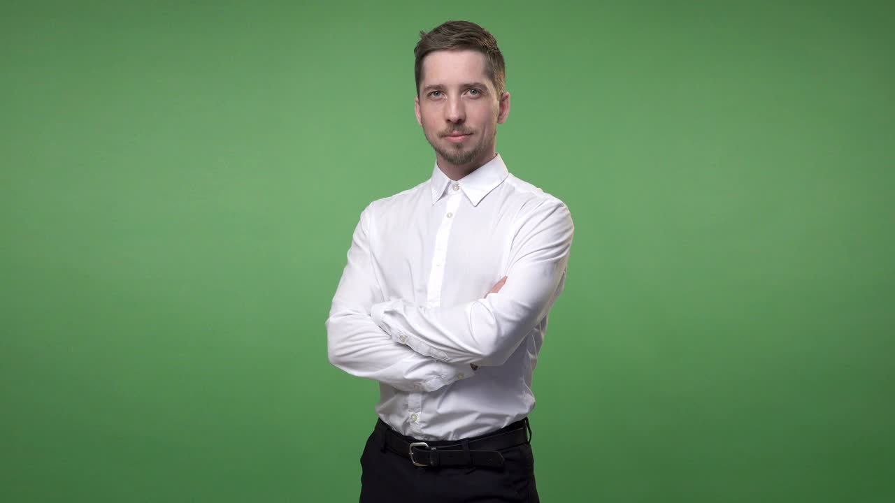 셔츠를 입은 잘생긴 젊은 남자가 손을 고 서 있으며, 크로마 키는 녹색 스크린 배경입니다.