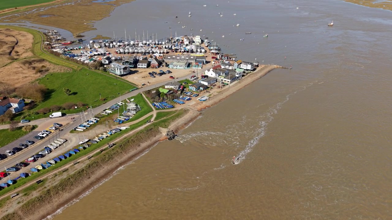 Volo in avanti di drone sopra barche a vela private e piccolo scalo per traghetti a Felixstowe Ferry