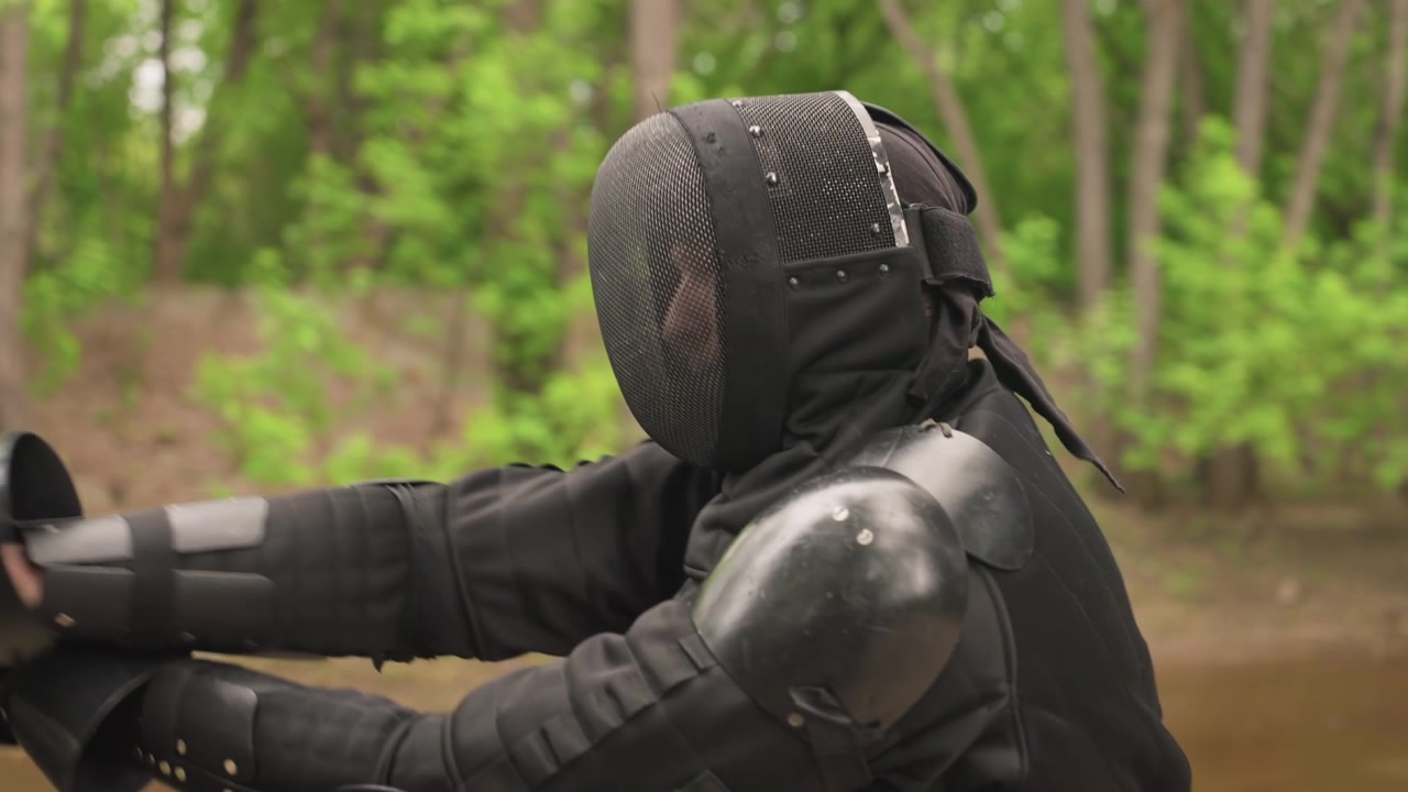 Close up of person in black fencing gear practicing sword techniques with another fencer. person demonstrates controlled movements and stances while holding blade interacting dynamically