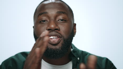 portrait of handsome african man sending air kiss to camera in studio.