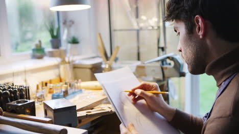Close Up Of Male Jeweller Sketching Out Design For Ring In Studio