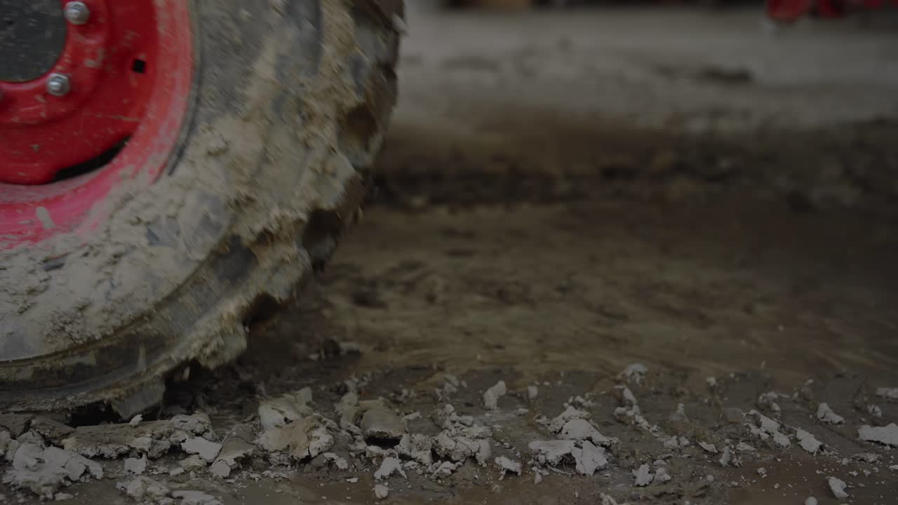 vista de cerca de la rueda del neumático del tractor embarrado saliendo del cuadro en cámara lenta cinematográfica