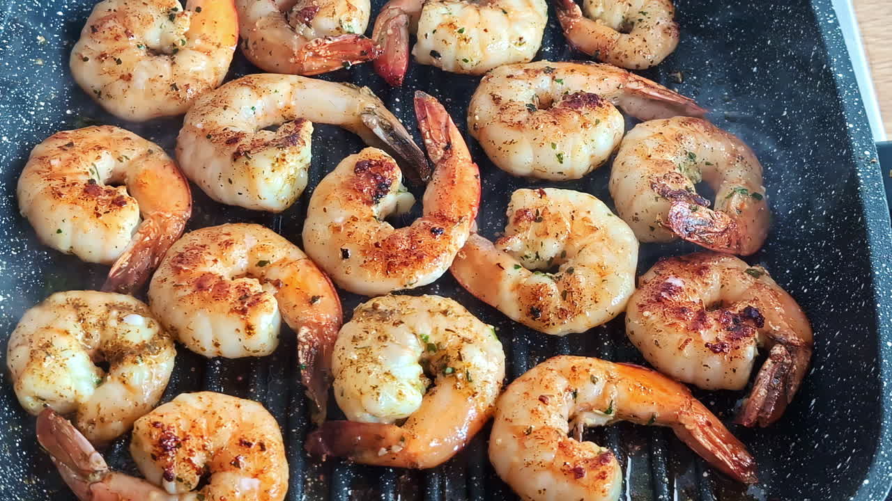 Juicy shrimps sizzle and brown in a hot pan during a cozy home cooking session.