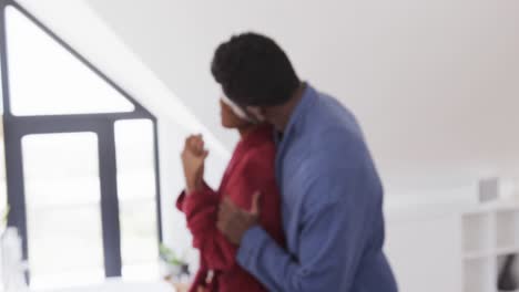 una feliz pareja afroamericana abrazándose y usando crema facial en el baño por la mañana, en cámara lenta.