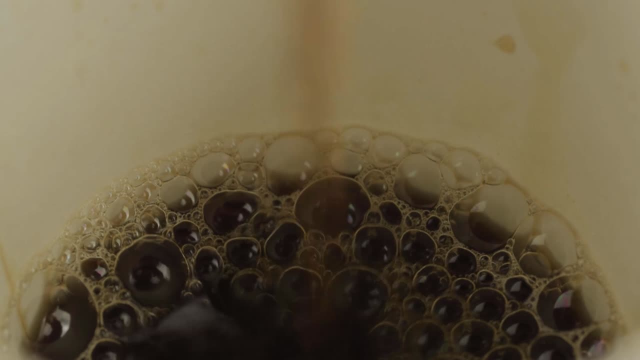 Bubbling coffee pouring into a cup macro shot
