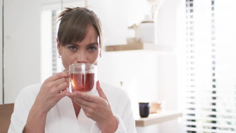 Middle-aged-Caucasian-woman-enjoys-a-warm-beverage-at-home,-with-copy-space