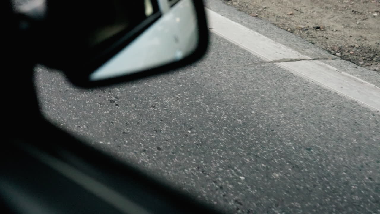 Closeup motion shot of asphalt road with clear marking captured from inside moving car, highlighting travel perspective, direction, speed, and texture of roadway