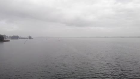 flying over calm waters on a hazy morning, overcast and hazy weather, a sailboat out on the water