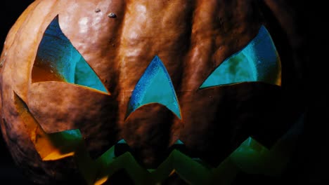 Halloween-pumpkin-with-a-scary-face-and-a-spider-on-the-eye,-illuminated-from-the-inside-multicolored-lights,-a-very-scary-pumpkin-for-Halloween