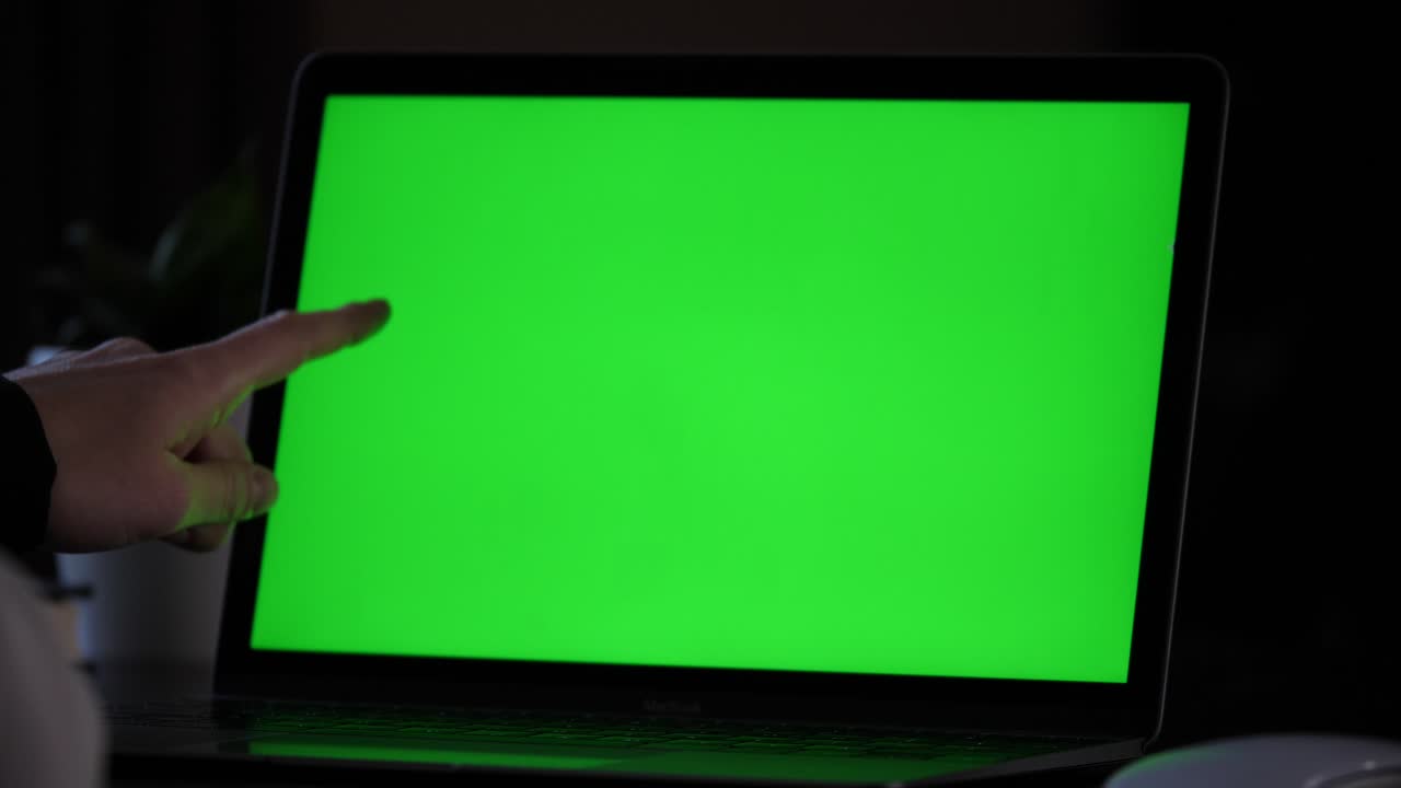 señalando con el dedo algo en la pantalla verde de un portátil, subrayando un texto leído con el dedo