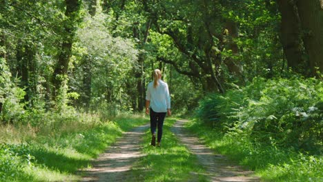 blonde woman walking through lush woods, slowmo zoom in