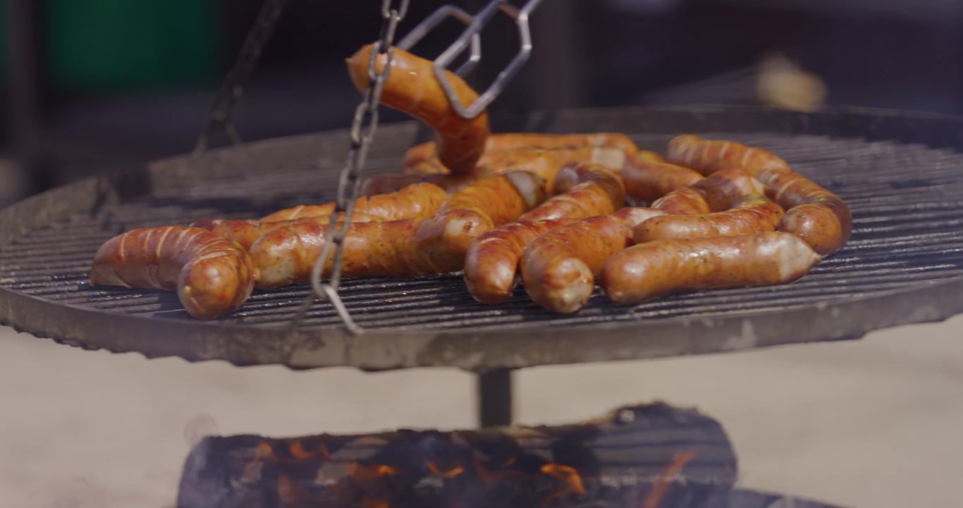 Primo piano di salsicce grigliate e girate su un barbecue