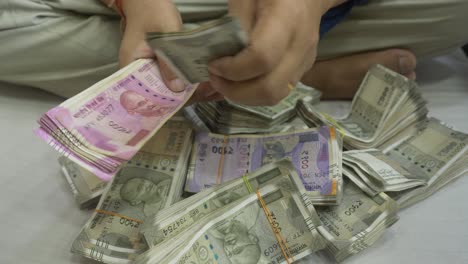 A-South-Asian-businessman-counting-2000-and-500-Rupee-banknotes,-Stack-of-Indian-banknotes,-Cash-in-Hand-Closeup,-India