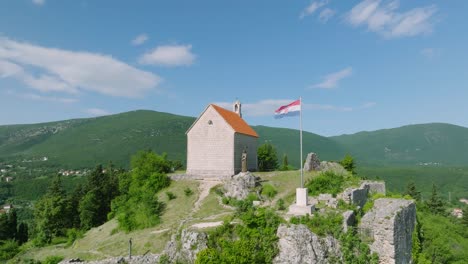 old medieval church on a hill in the mountain town sinj, croatia, aerial dolly