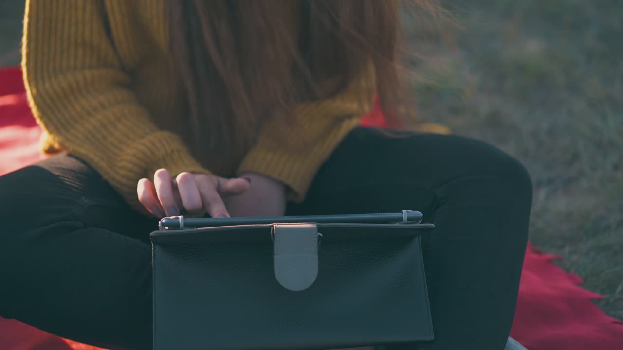 소녀 는 저녁 에 캠핑장 에서  ⁇ 은 플레이드 에 앉아 있는 태블릿 을 사용 한다