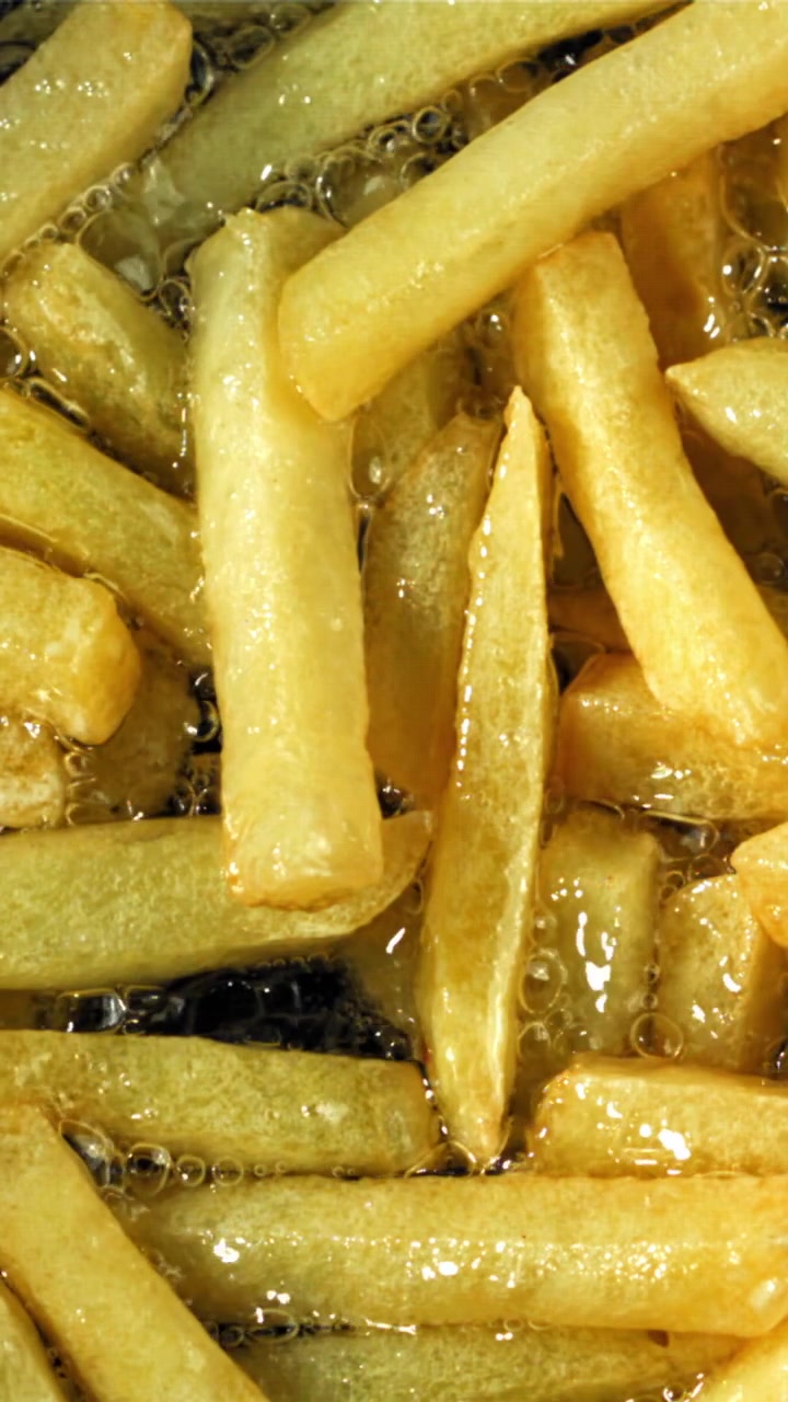 Patatas fritas doradas friéndose en aceite caliente burbujeante