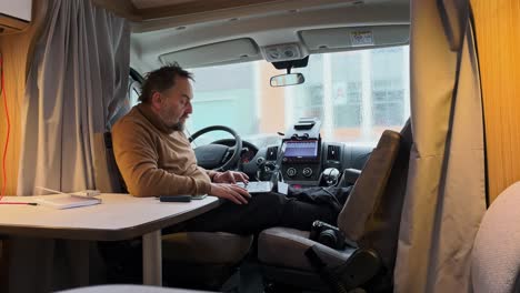 senior man using laptop in campervan, digital nomad vanlife concept