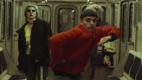 Young-Trendy-Dressed-Man-Dancing-with-Two-Girls-in-Metro