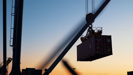 dynamic operation of a crane hoisting shipping containers against a stunning sunset background captured in two sequential frames